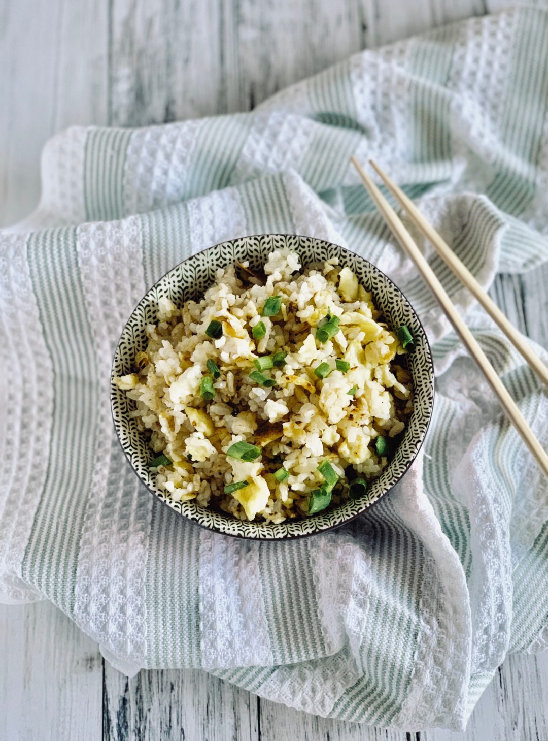 bowl of fried rice containing eggs, soy sauce, green onions and salt and pepper to taste